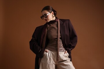Young woman in stylish clothes on brown background