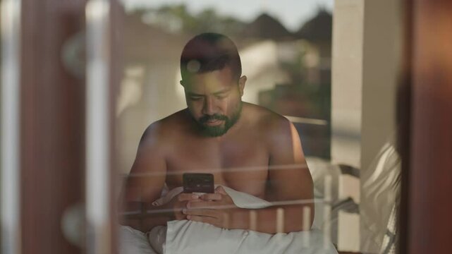 Brown Asian man types on phone with anxious expression, struggling with heavy emotions in silence. A moment of tension, overthinking, and emotional vulnerability.