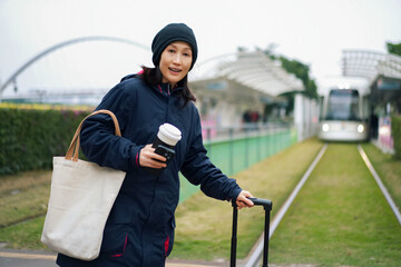 Woman Waiting for Tram with Coffee and Bag