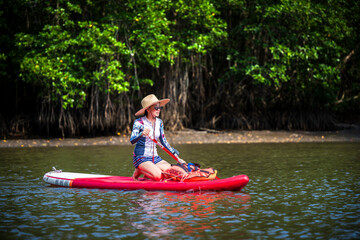 Women enjoy standup paddle board in the natural lake river of rainforest