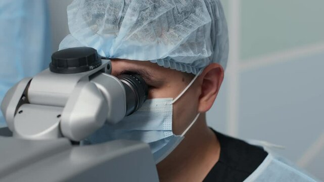 Medium closeup pf masked ophthalmic surgeon closely examining patient eye using high-precision operating microscope during delicate eye procedure.