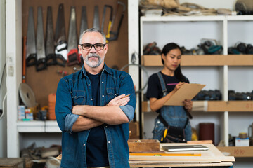 Carpenter, Wood workshop. Portrait of senior carpenter man standing with crossed arms in carpenter wood factory