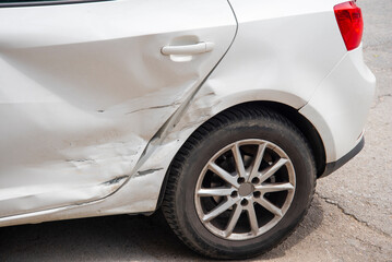 Car with visible damage parked on a city street during daytime in an urban environment