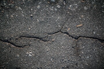 Detailed view of old asphalt, featuring a network of cracks and imperfections, telling a story of years of use.