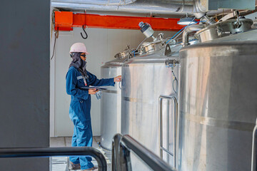 Male work inspection process stainless steel tanks and pipe with pressure meter in equipment tank facility for drink cellar at the with vertical stainless