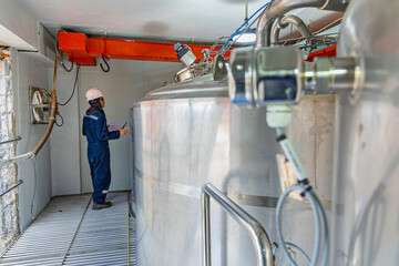 Male work inspection process stainless steel tanks and pipe with pressure meter in equipment tank...