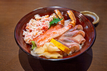 Premium fresh raw seafood mixed rice bowl (Kaisen-don, Japanese tasty food), Japanese Rice with sashimi of salmon, zuwai kani crab on wood background