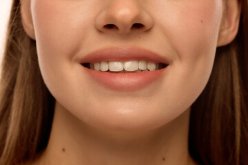Fototapeta premium Woman smiling with white teeth, natural pink lips, glowing cheekbones and smooth skin. Female model with natural make-up. Concept of dental health, beauty, natural smile, treatment