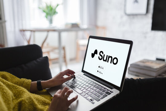 Woman using laptop showing suno app website in living room