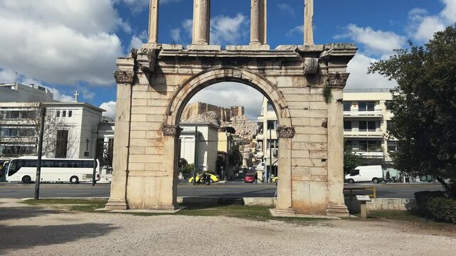 Athens, Greece - Mar 10, 2024: Arch of Hadrian and Acropolis at background. Hadrian’s Gate is known as gateway to Temple of Olympian Zeus, Olympieion, in ancient city old town