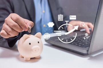 A person deposits a coin into a piggy bank beside a laptop, symbolizing online savings, financial planning, and time management.