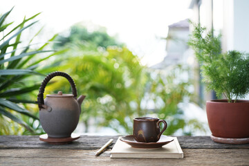 A vintage earthenware tea set with a notebook placed on a rustic wooden table