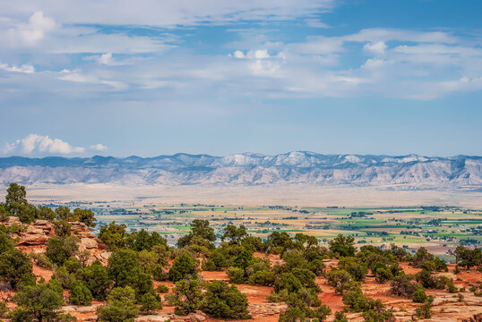 Widescreen full-frame view of Grand Valley farmlands looking northwest toward the distant Roan Plateau oil shale formations in Colorado