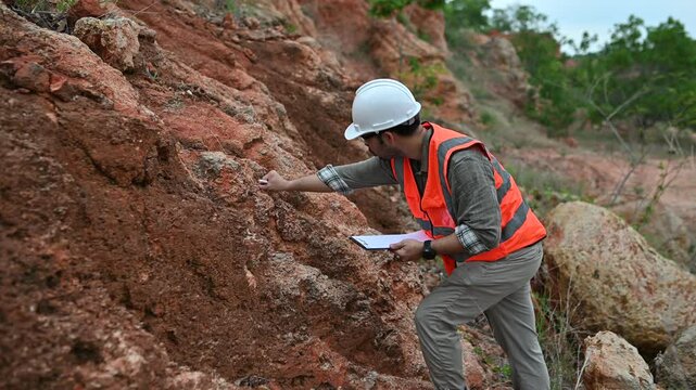 A geologist is using a steel rod to drill into a rock to obtain a rock sample for analysis