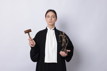Judge with mallet and figure of Lady Justice on light background