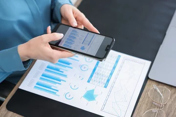 Gordijnen Woman taking photo of document using scanning app on smartphone at desk in office, closeup © New Africa