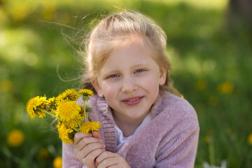 Cute little girl with beautiful dandelions outdoors
