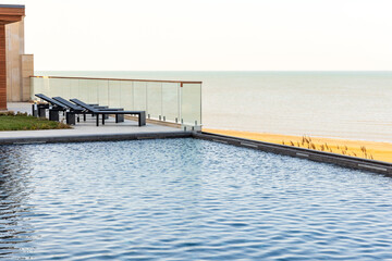 A beautiful seaside terrace features a luxurious pool, elegant lounge chairs