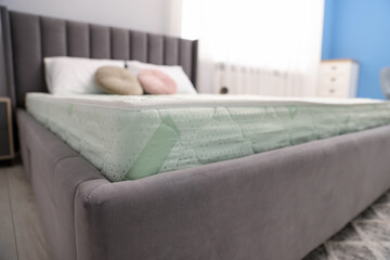 Comfortable bed with new soft mattress and pillows indoors, closeup