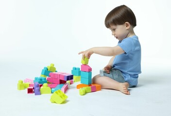 Cute little boy playing with building bricks on white background