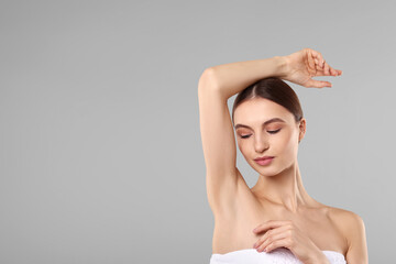 Young woman showing smooth skin after epilation on gray background, space for text