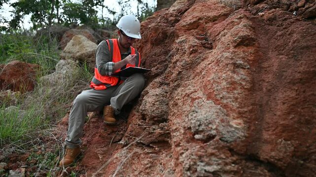 A geologist is using a steel rod to drill into a rock to obtain a rock sample for analysis