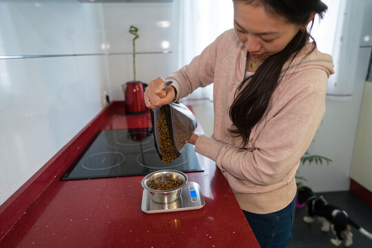 Woman measuring dog food on a red kitchen counter