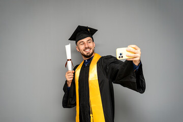 Happy graduate taking a selfie with diploma and smartphone