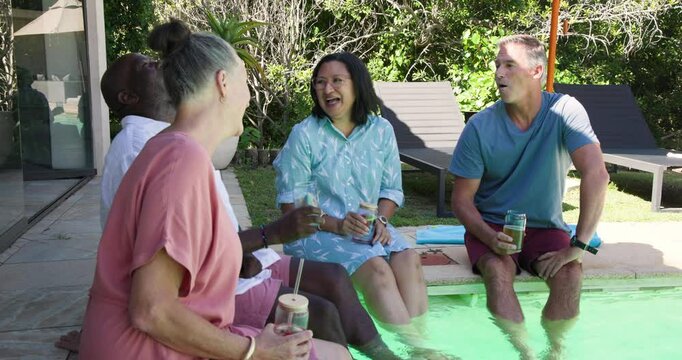 Diverse friends enjoying drinks and laughter in garden, sharing joyful moments together