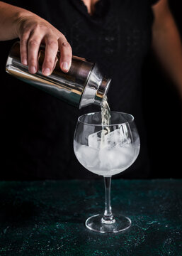 Pouring a refreshing gin tonic over ice cubes