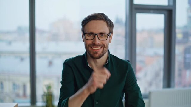 Portrait friendly entrepreneur pointing finger to camera at contemporary office.