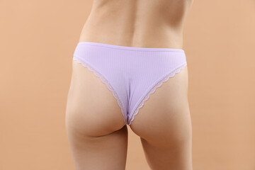 Woman wearing beautiful underwear on beige background, closeup
