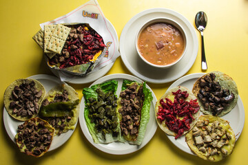 In this lush display, a bowl of charro beans is surrounded by various styles of tacos, set against a brightly colored table that invites camaraderie and shared culinary experiences.