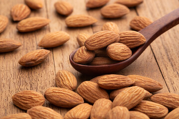Almonds in wooden spoon on wooden table.Heap of almond