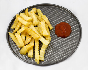 A visually appealing arrangement of golden crinkle cut fries next to a bowl of ketchup, ideal for sharing or enjoying as an afternoon snack or party appetizer.