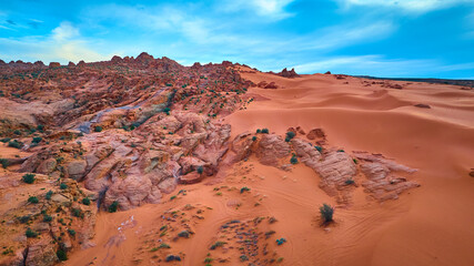 Aerial Red Rock Ridges and Sand Dunes in Motion Over Desert Landscape