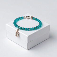 Turquoise gemstone bracelet with 925 sterling silver charm shaped as the letter B, displayed on a white jewelry box, elegant accessory in minimal product shot style