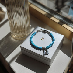 Turquoise gemstone bracelet with 925 sterling silver charm shaped as the letter B, displayed on a white jewelry box, elegant accessory in minimal product shot style
