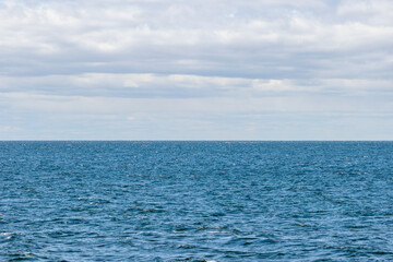 Obraz premium The dark blue water of Geren Bay, looking west from Peninsula State Park, Door County, Fish Creek, Wisconsin, under a partly cloudy sky in late May