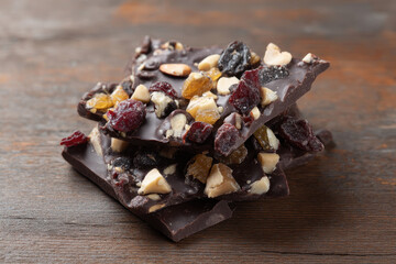 Dark chocolate bark with nuts and dried fruits on wooden table