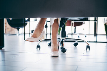 Businesswoman in an office wearing elegant high heels while sitting at a desk in a professional and...
