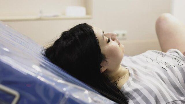 A woman with painful contractions lies in a hospital bed awaiting labor. The concept of successful labor and midwifery care.