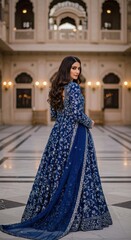 A woman showcases an exquisite blue embroidered gown in a stunning historic palace backdrop