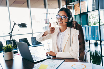 Confident businesswoman working in an office, providing assistance through a headset, projecting...