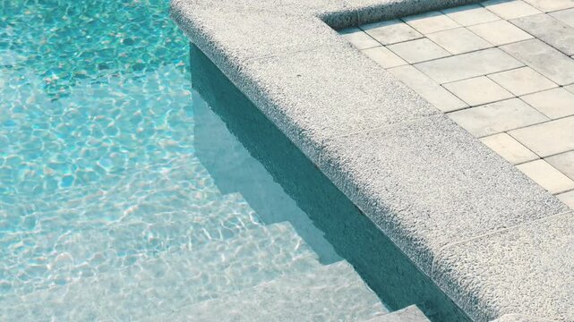 Clear blue water in the pool. Steps into the pool. The edge of the pool is finished with a gray curbstone. Relaxation in the backyard of a country house
