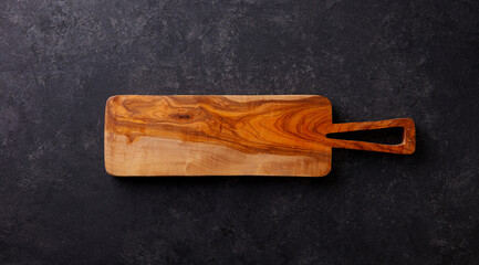 Acacia cutting board for serving cheese. Copy space for design elements or text. Anthracite stone background. Close up.