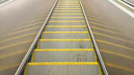 Fototapeta premium Empty Yellow-Lined Escalator Steps in Urban Subway Station. Concept of City Mobility, Public Transport, Commuting Infrastructure and Minimalist Architecture for Editorial or Commercial Use