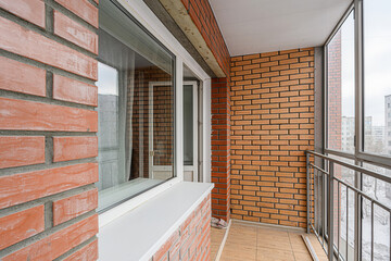 view from a brick-clad balcony with large windows and metal railings, overlooking a cityscape on a...
