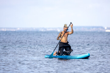Man paddle surfing with a dog.