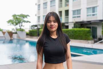 Young woman posing next to swimming pool during summer
